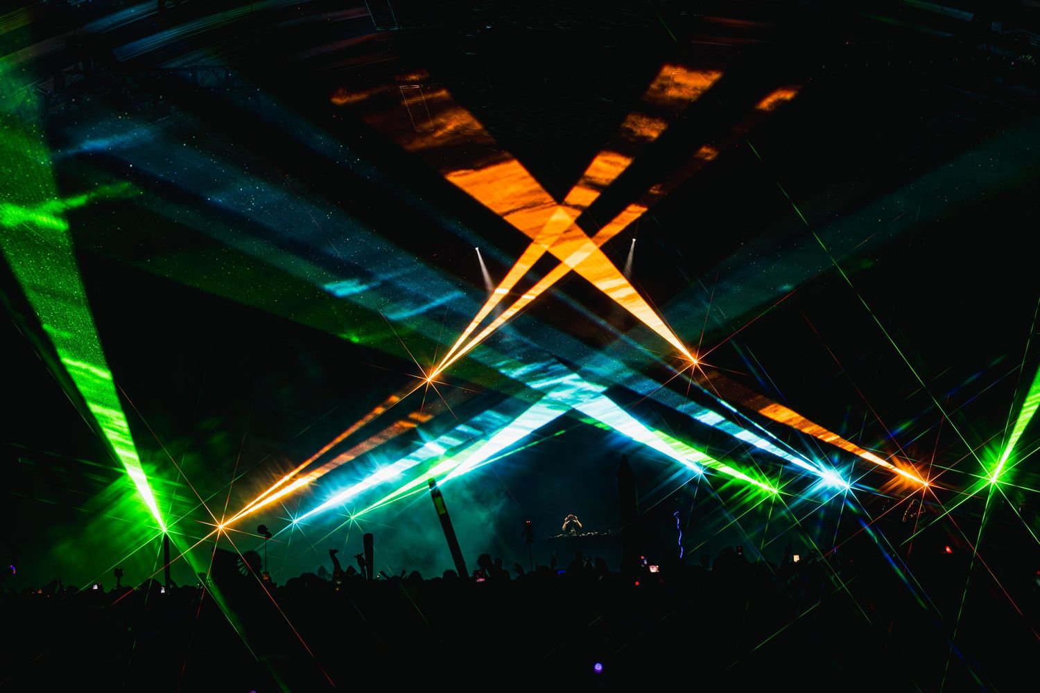 Colorful laser beams create dynamic light patterns in a dark space during an entertainment show.