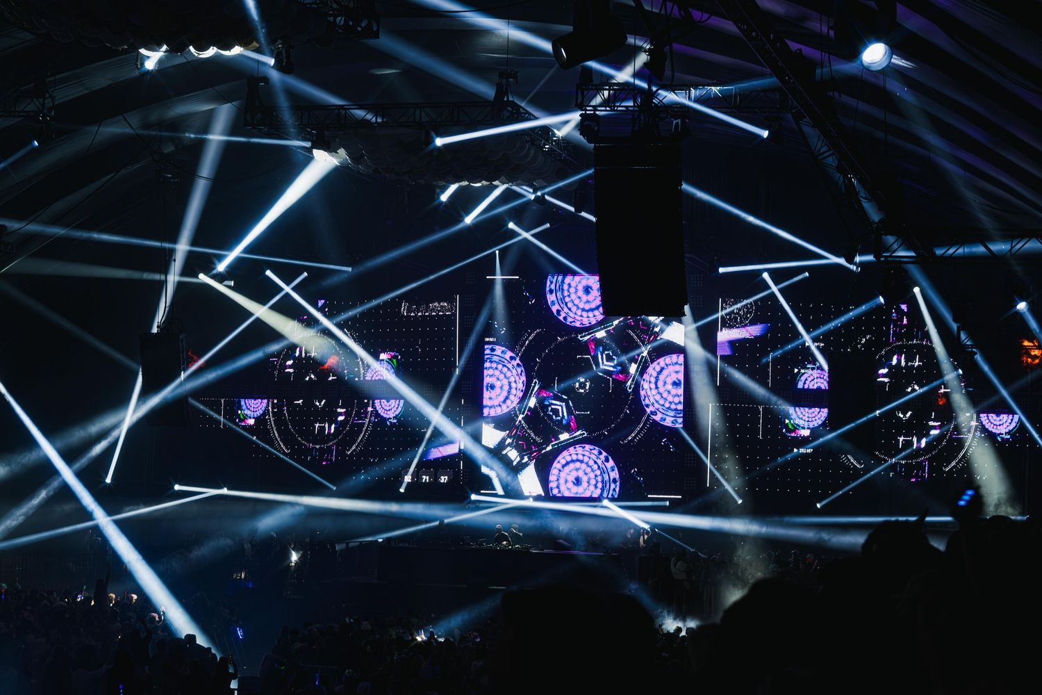 Concert stage illuminated with dramatic blue and purple lighting beams creating an atmospheric performance environment.