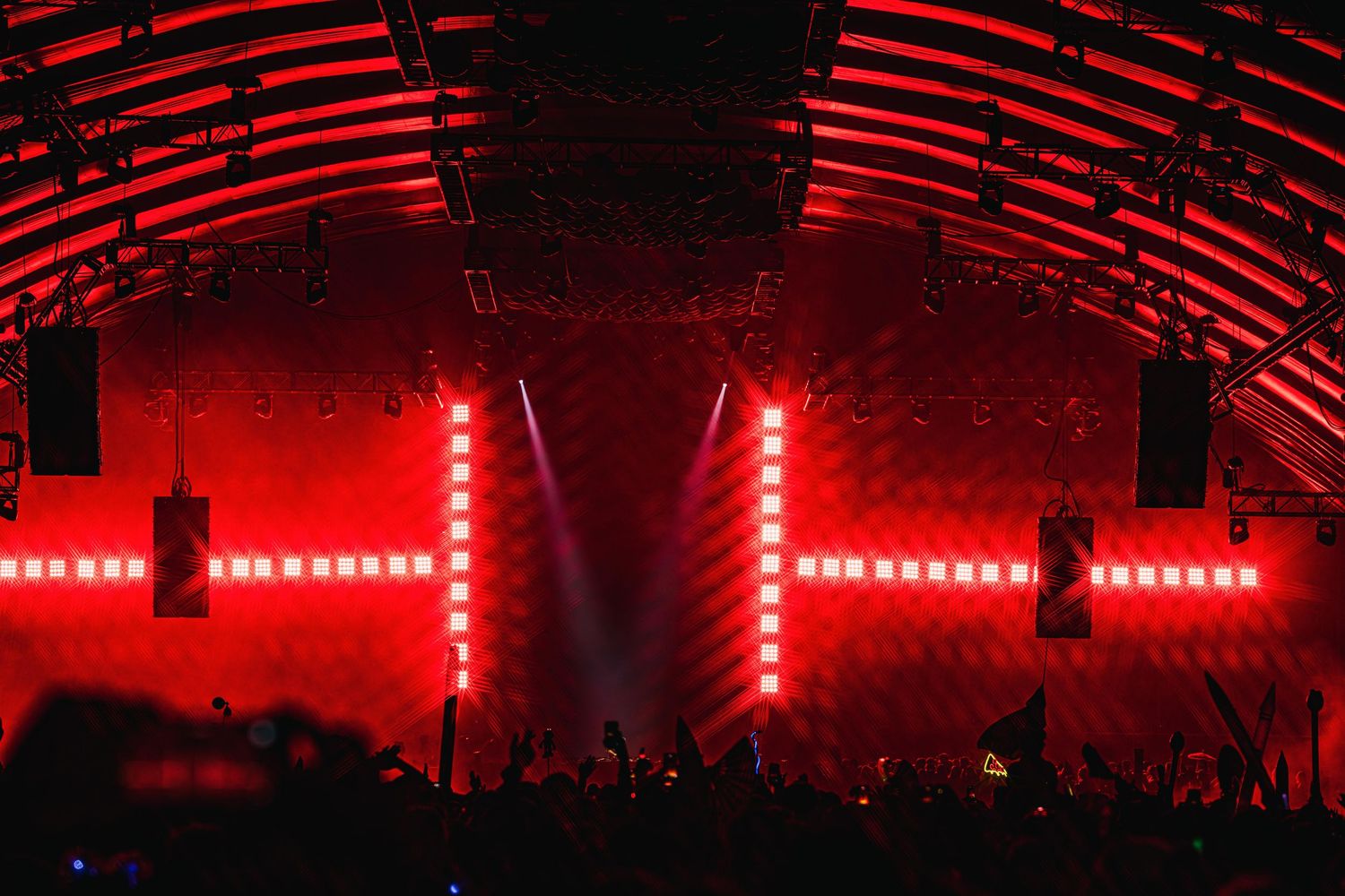 Concert venue illuminated with dramatic red lighting and LED strips creating an immersive atmosphere during performance.