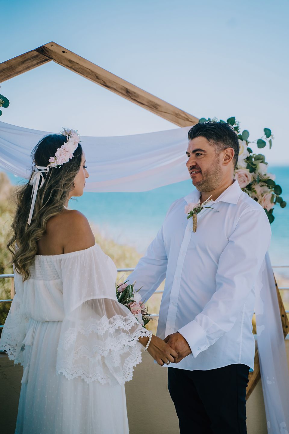 A couple shares an intimate moment under a white canopy at their outdoor wedding ceremony.