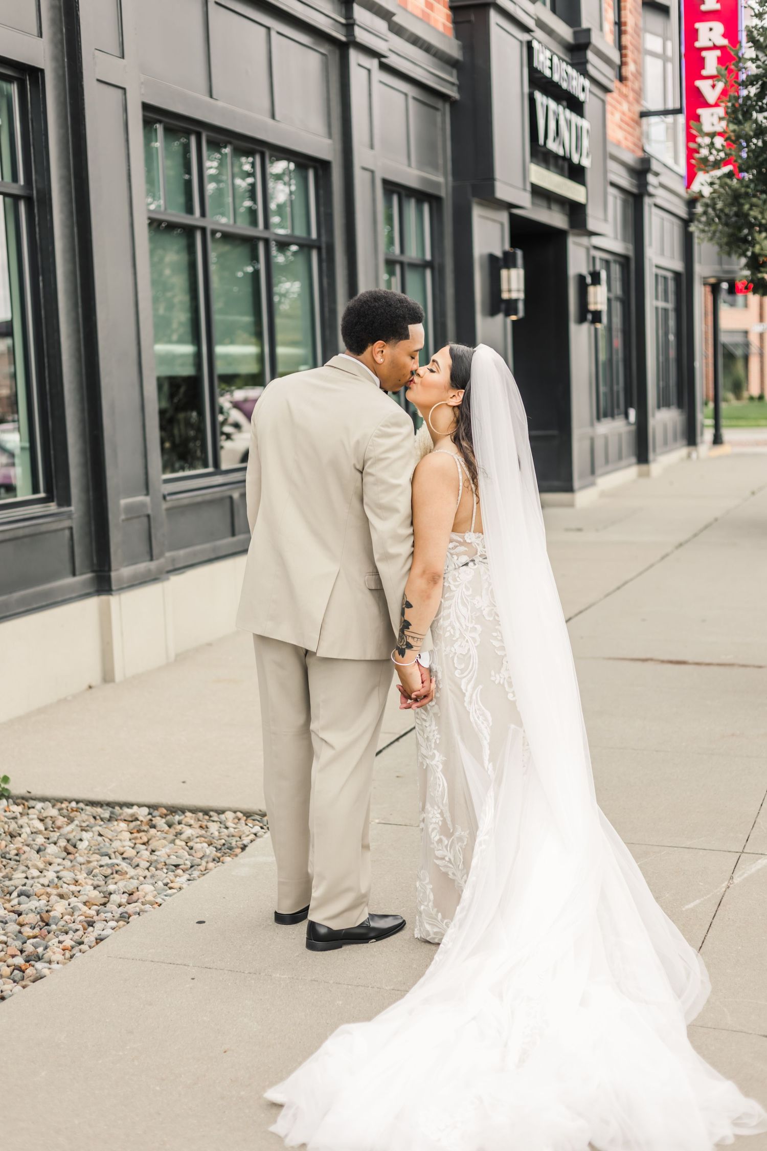 bride and groom bridal portraits kissing in front of their venue at the district in Ankeny