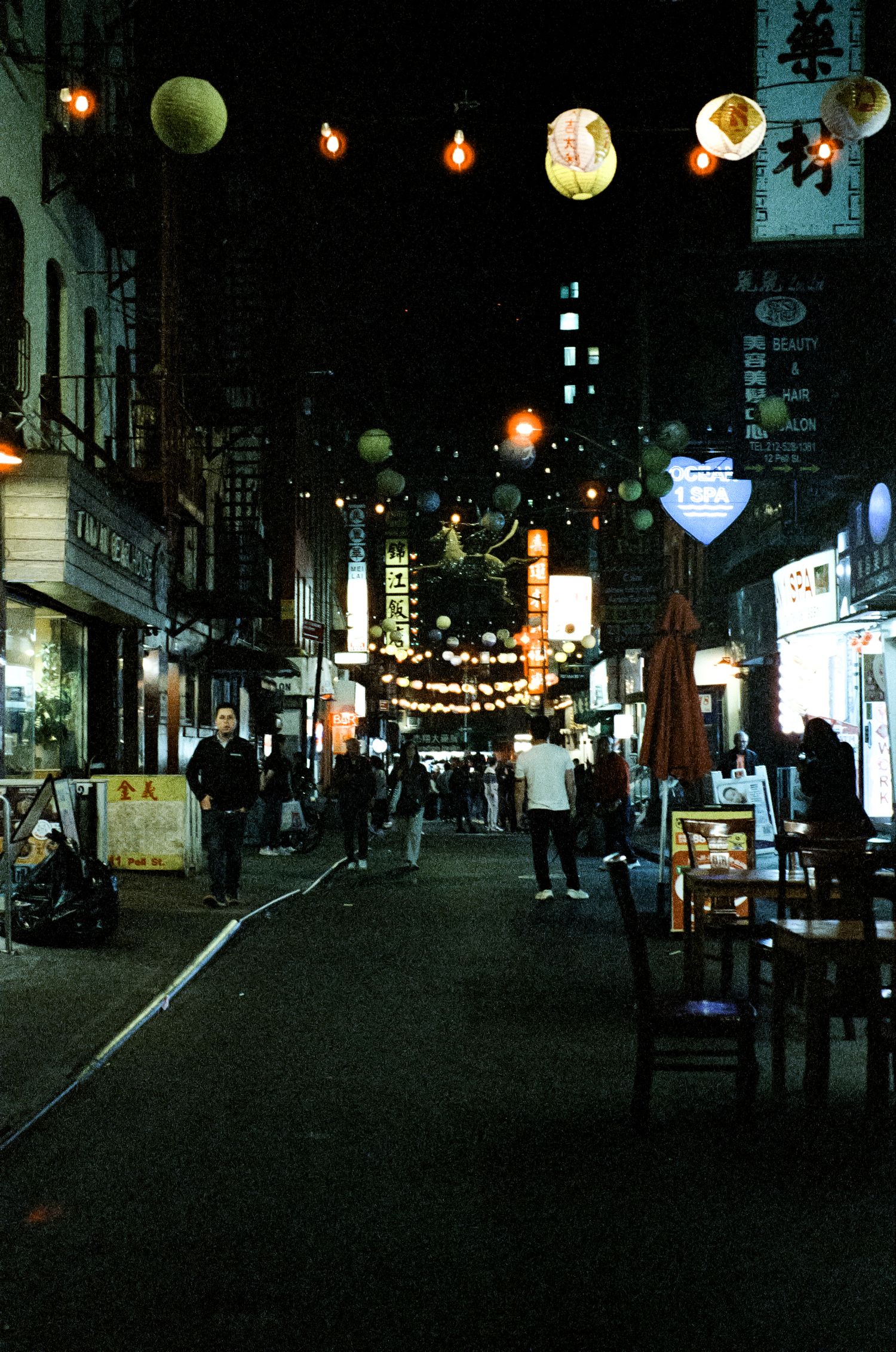 Lantern-lit alley in Japan with paper lanterns strung across the narrow street at night.