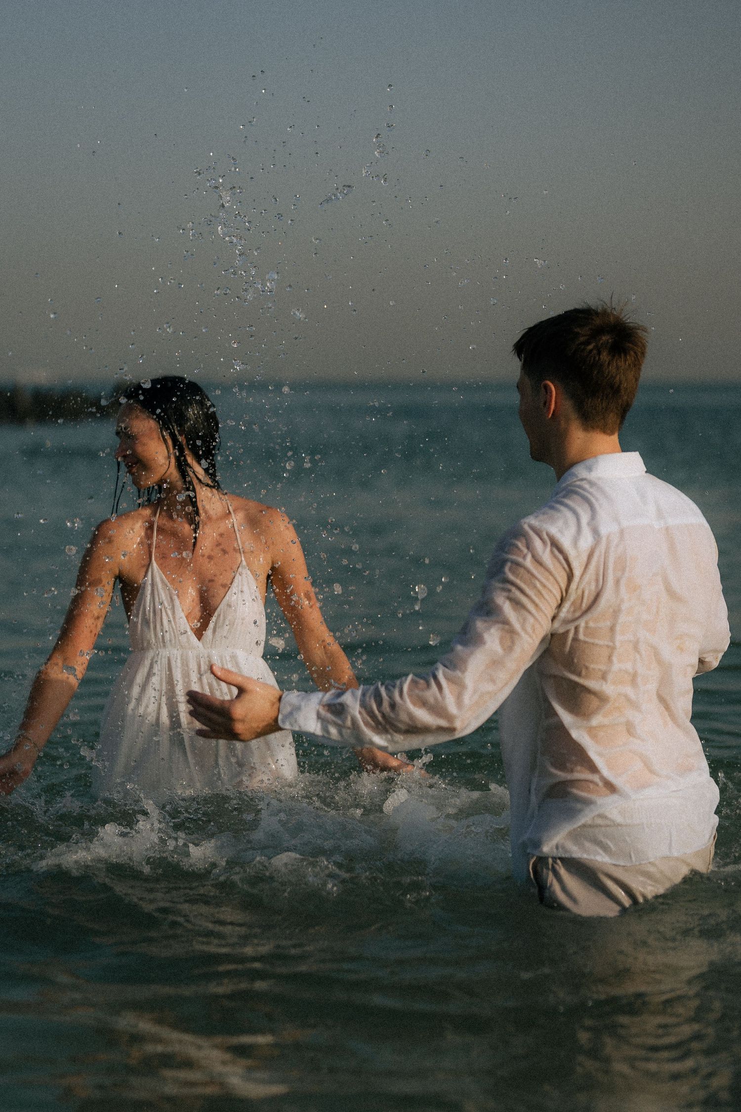 Playful couple running into the sea during Dubai beach session