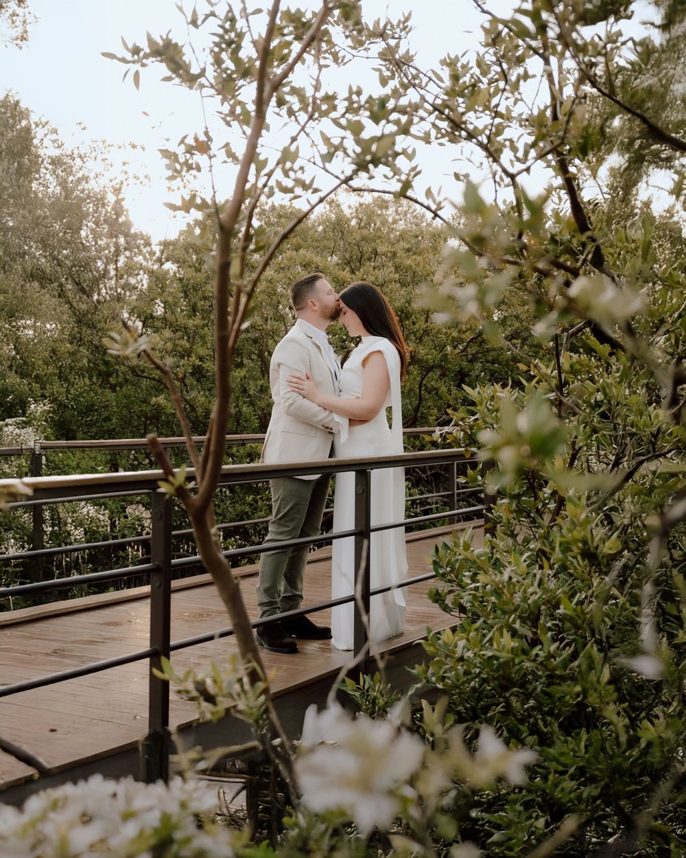 Bride and groom embracing among lush greenery during outdoor wedding photography session