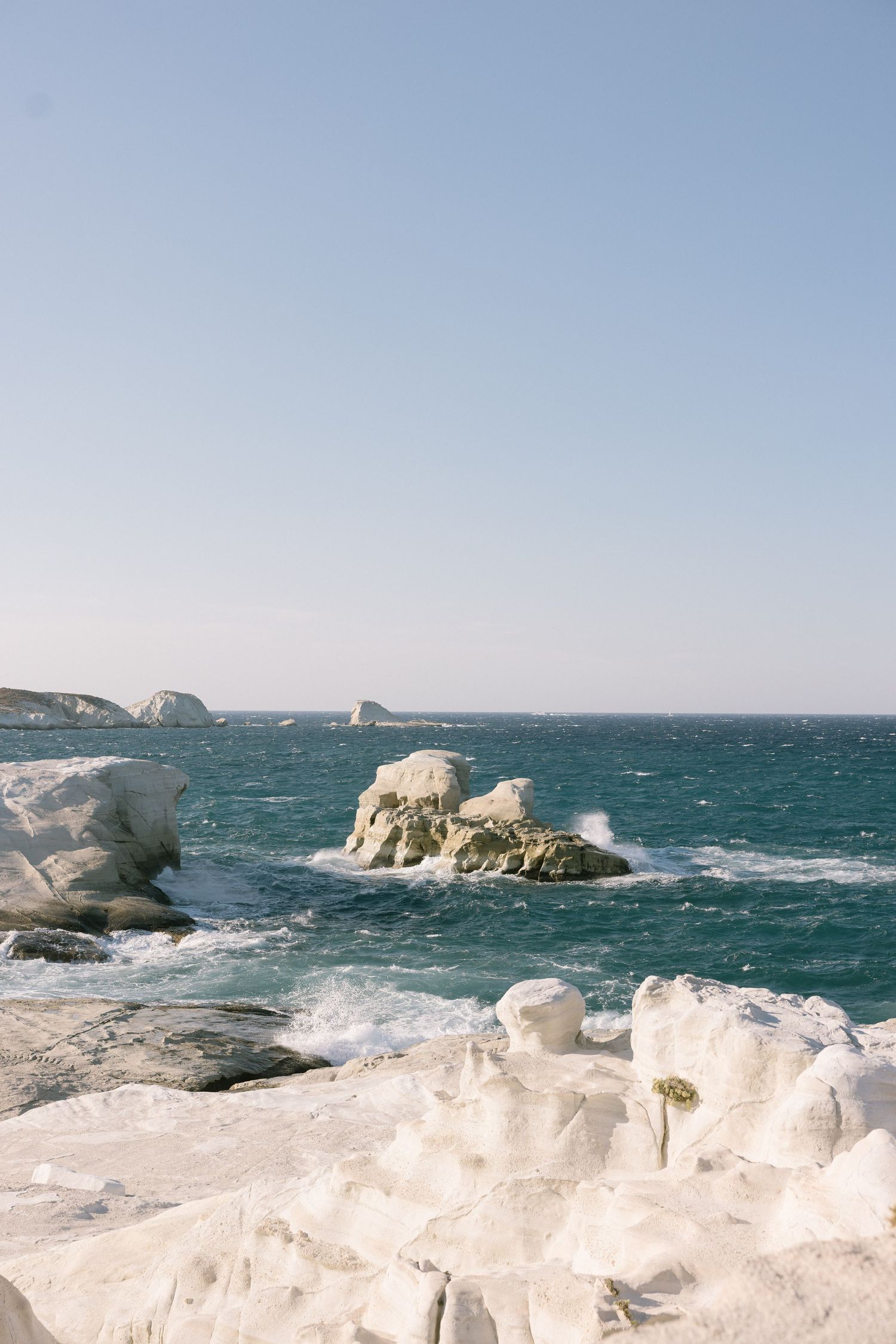 Dramatic coastal seascape with waves crashing against ice-covered rocks along a winter shoreline.