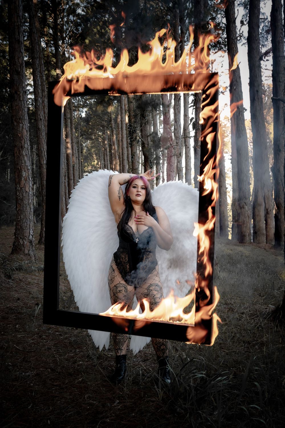 A surreal photo series showing a burning mirror reflecting a figure in a white dress among dark forest trees.