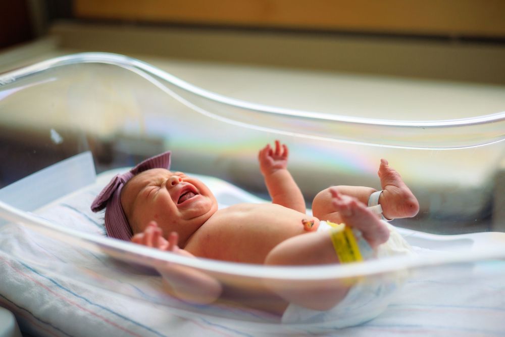 Newborn baby resting peacefully in a hospital bassinet while being monitored.