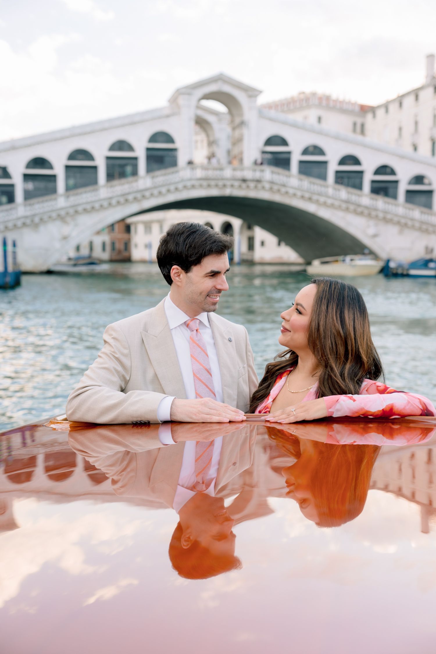 A couple enjoys a romantic moment in a water taxi near the iconic Rialto Bridge in Venice, Italy.
