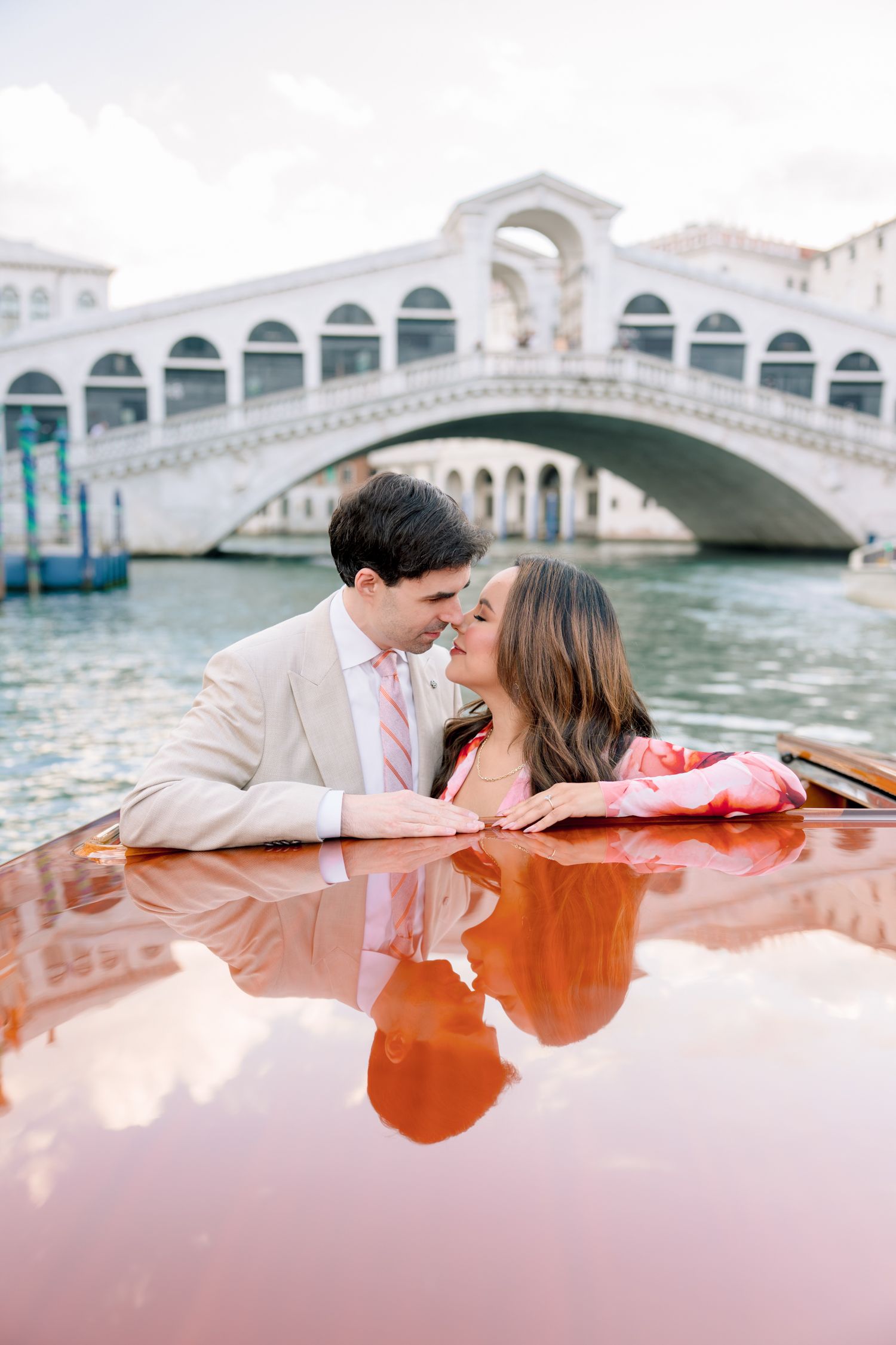 A romantic couple shares an intimate moment while riding in a wooden boat along Venice's scenic canals.