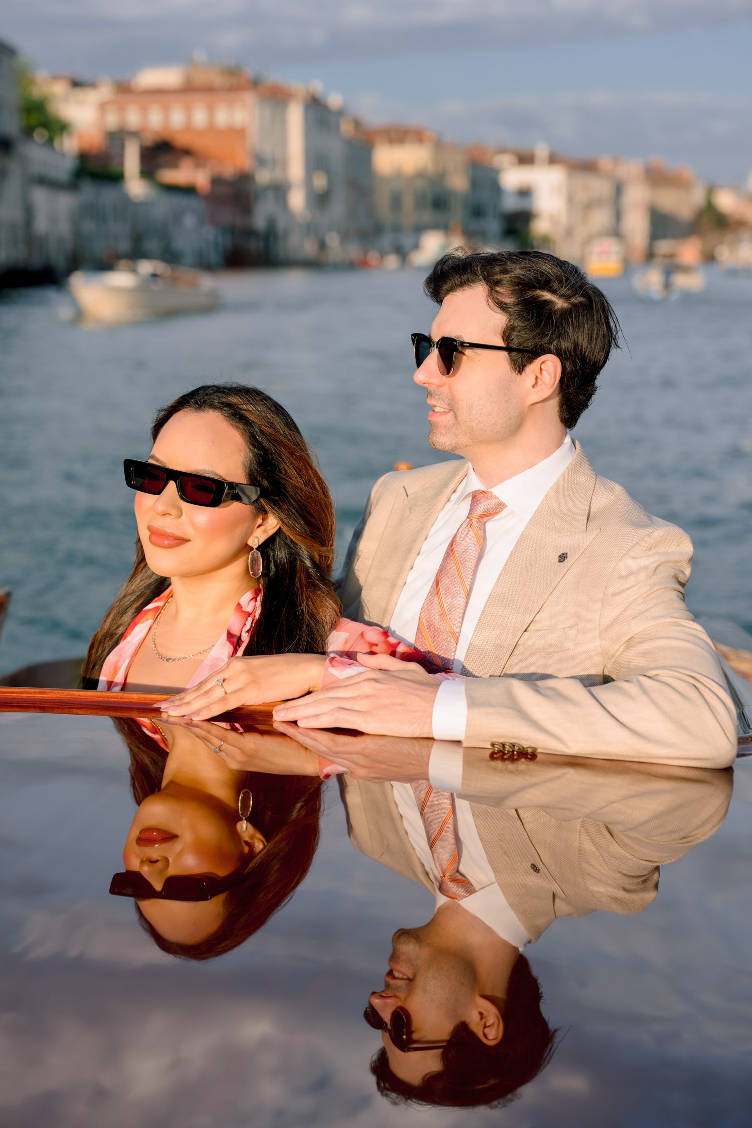 Couple in matching outfits enjoying a romantic boat ride along Venice canals during golden hour.