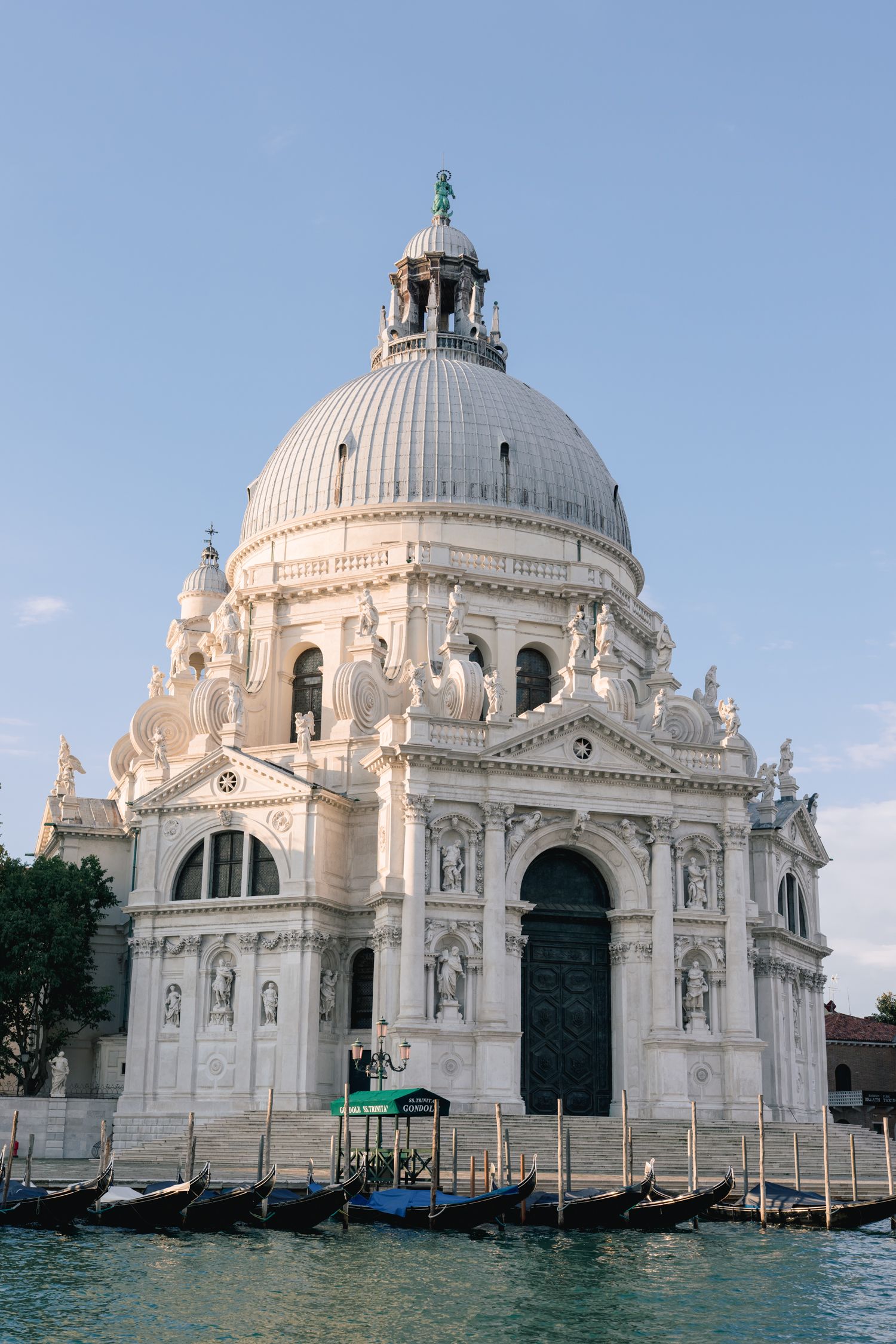 Four views of the iconic white marble Santa Maria della Salute church in Venice with its grand domes reflected in floodwaters.