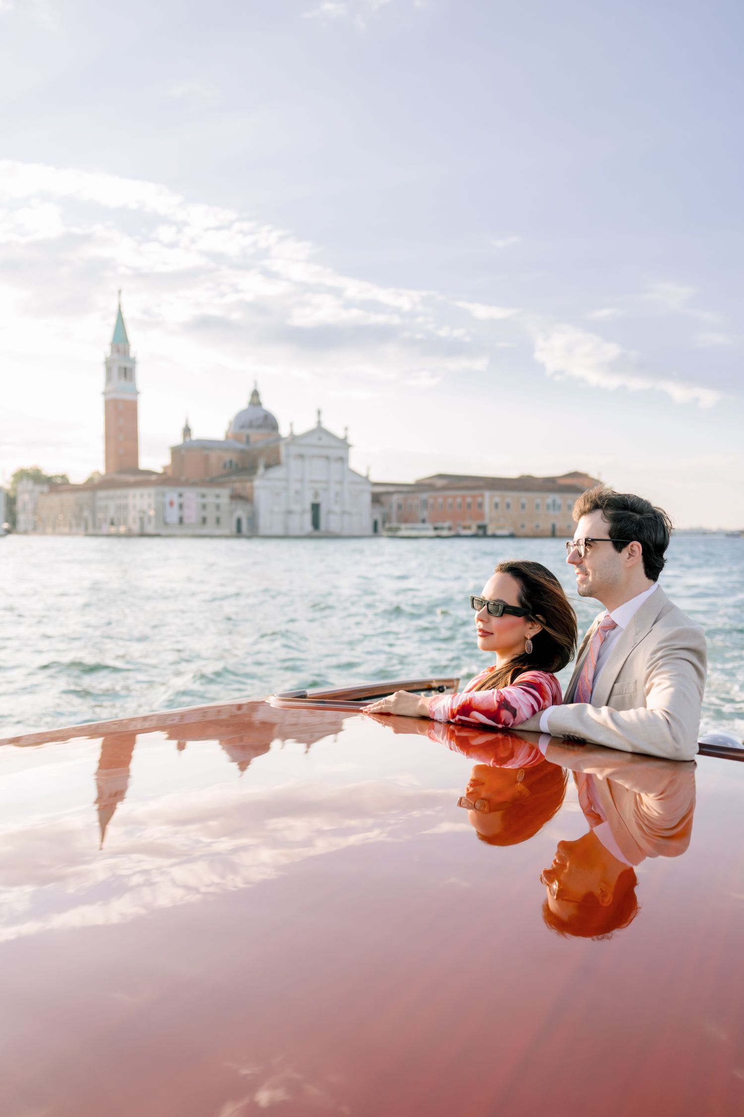 A couple enjoys a romantic boat ride in Venice with the iconic San Giorgio Maggiore church in the background.