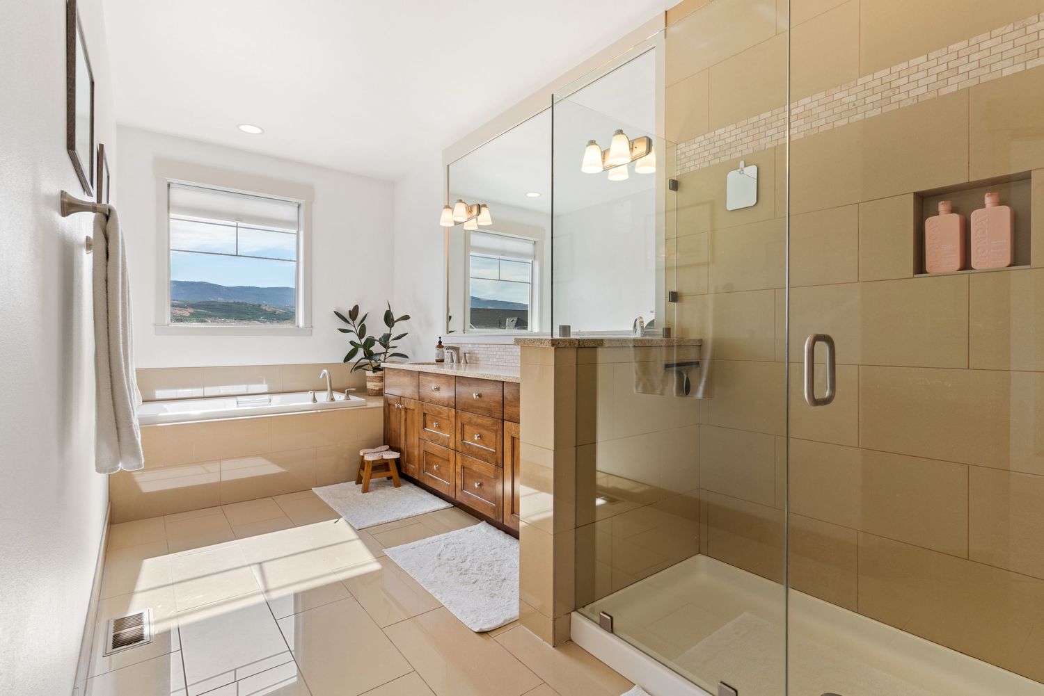 Bright luxury bathroom with glass shower, soaking tub, and modern finishes in residential home in Wenatchee, WA.