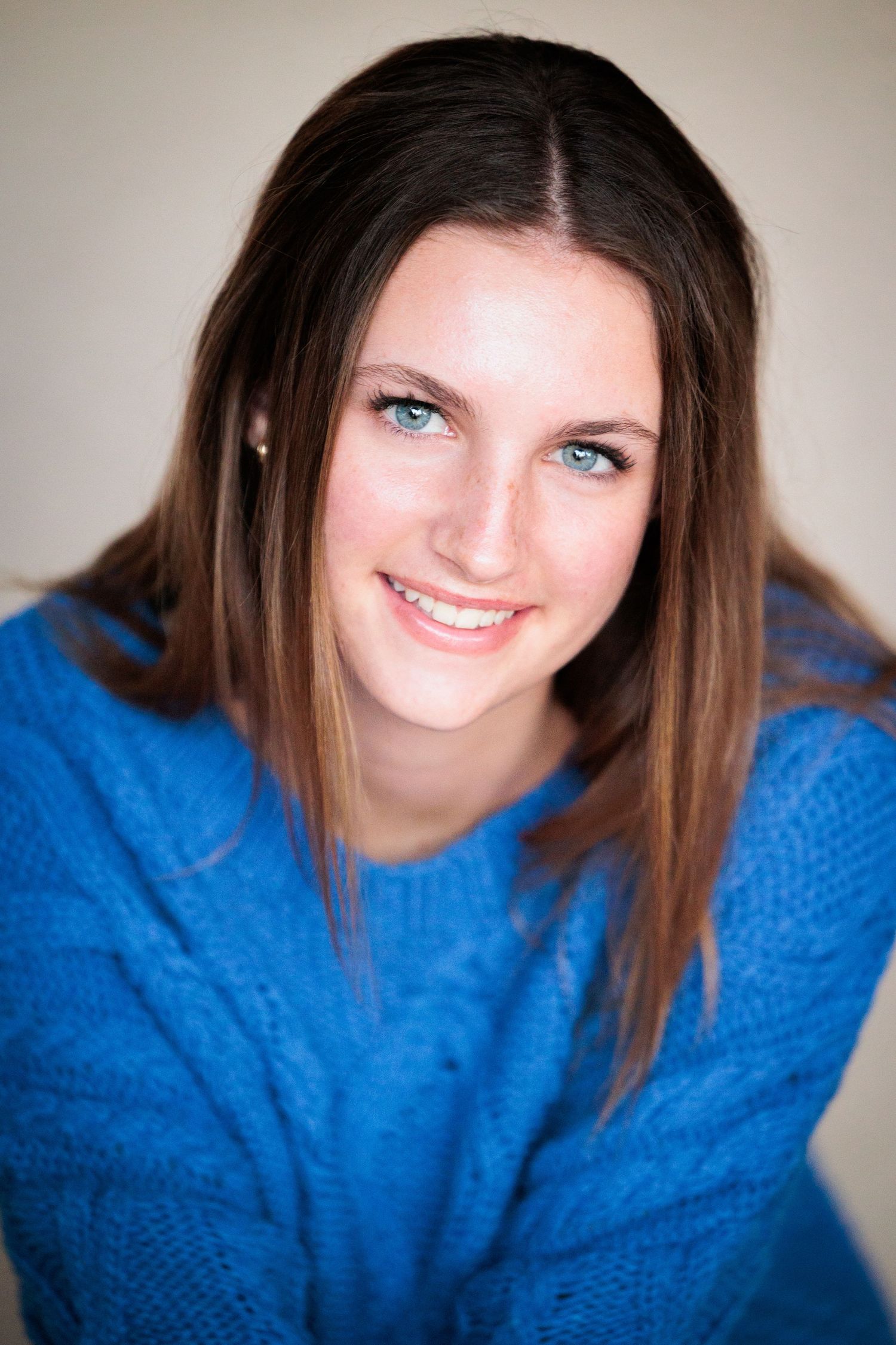 Young woman with blue eyes smiling in a blue knit sweater for a portrait photo.