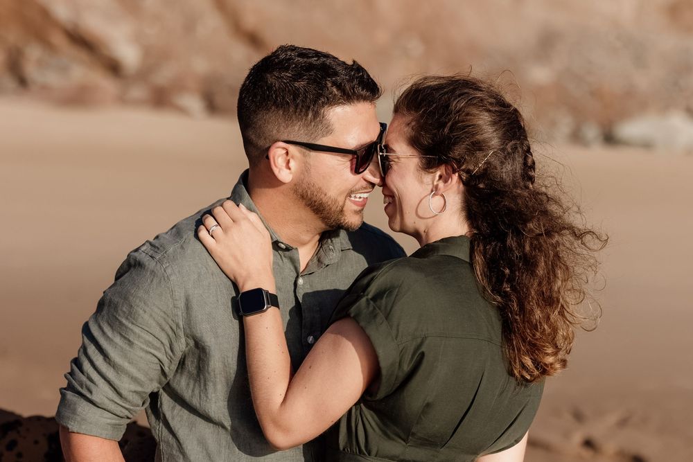 A young couple embracing and looking affectionately at each other in a natural outdoor setting.