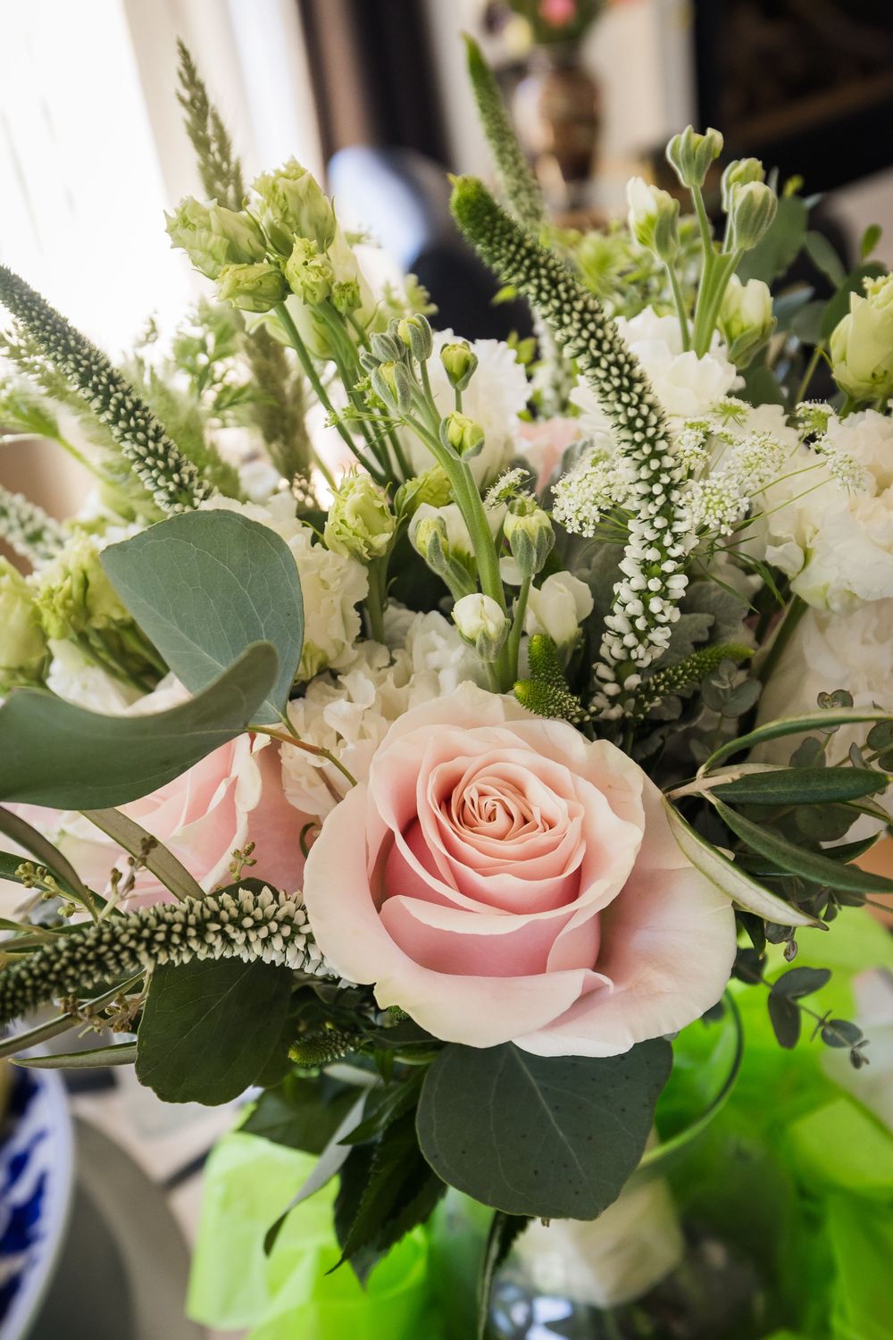 Elegant wedding bouquet with pink roses, white flowers, and eucalyptus greenery arranged in a vase.