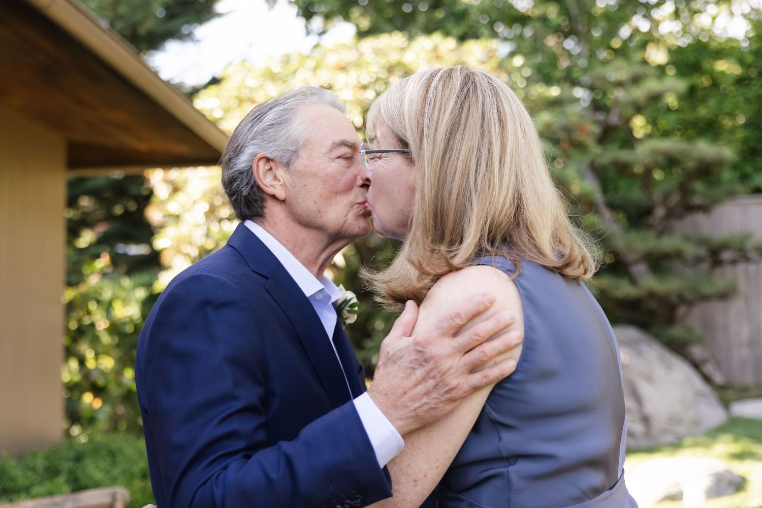 A romantic couple shares a tender kiss in a garden setting during an outdoor photo session.