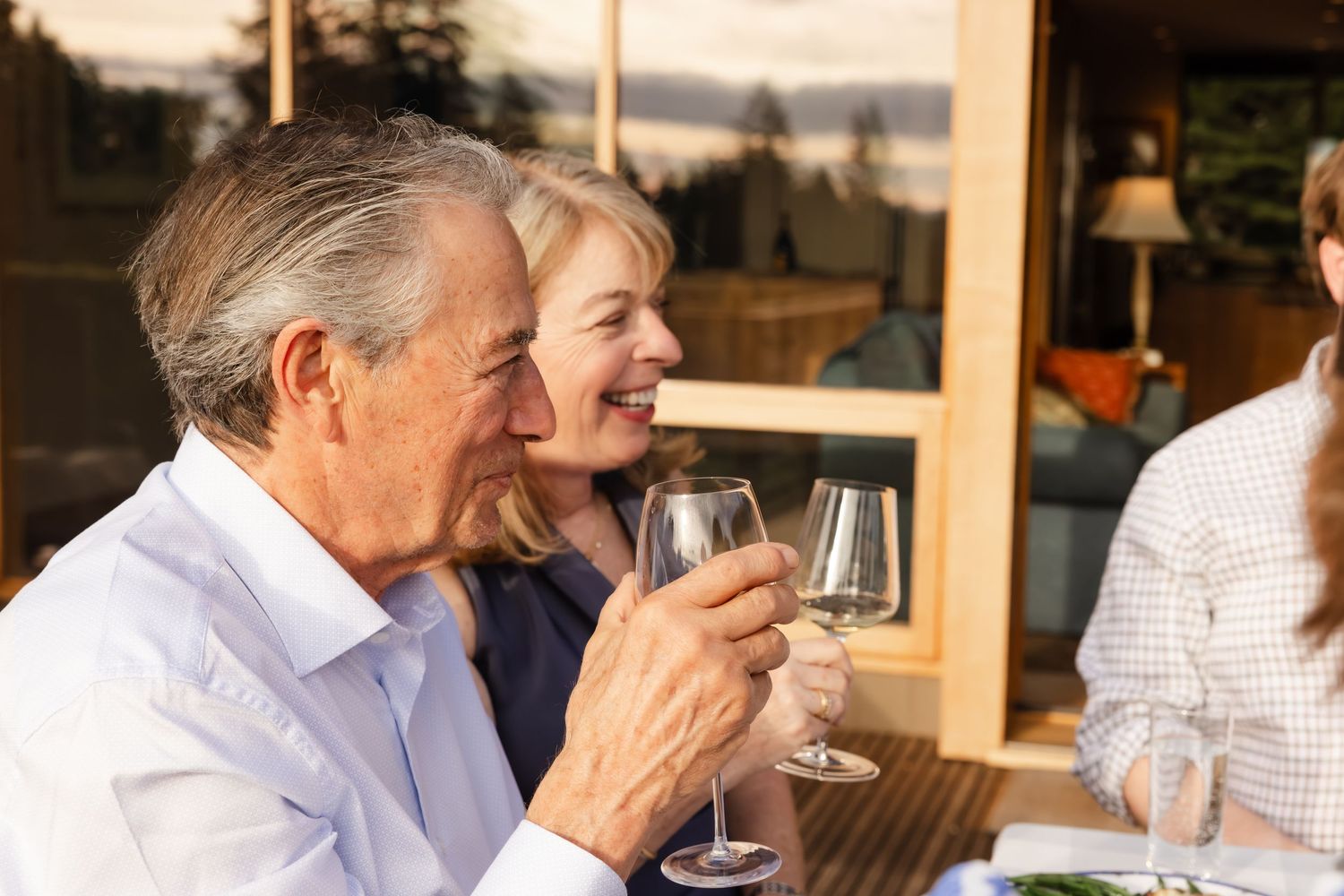 People enjoying wine and conversation at an outdoor restaurant patio during sunset.