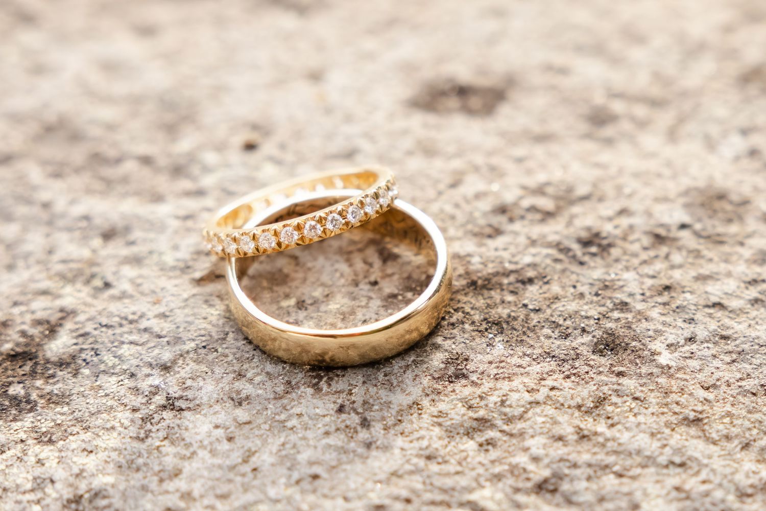 Seven close-up photos of gold wedding rings with diamonds arranged in sequence on a textured beige surface.