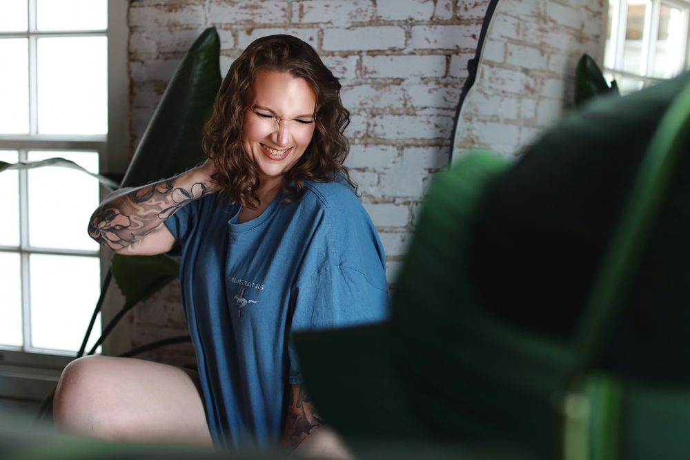 Casual indoor portrait in blue shirt against white brick wall.