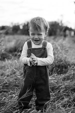 Black and white photo sequence showing a small child in overalls playing outdoors in tall grass.