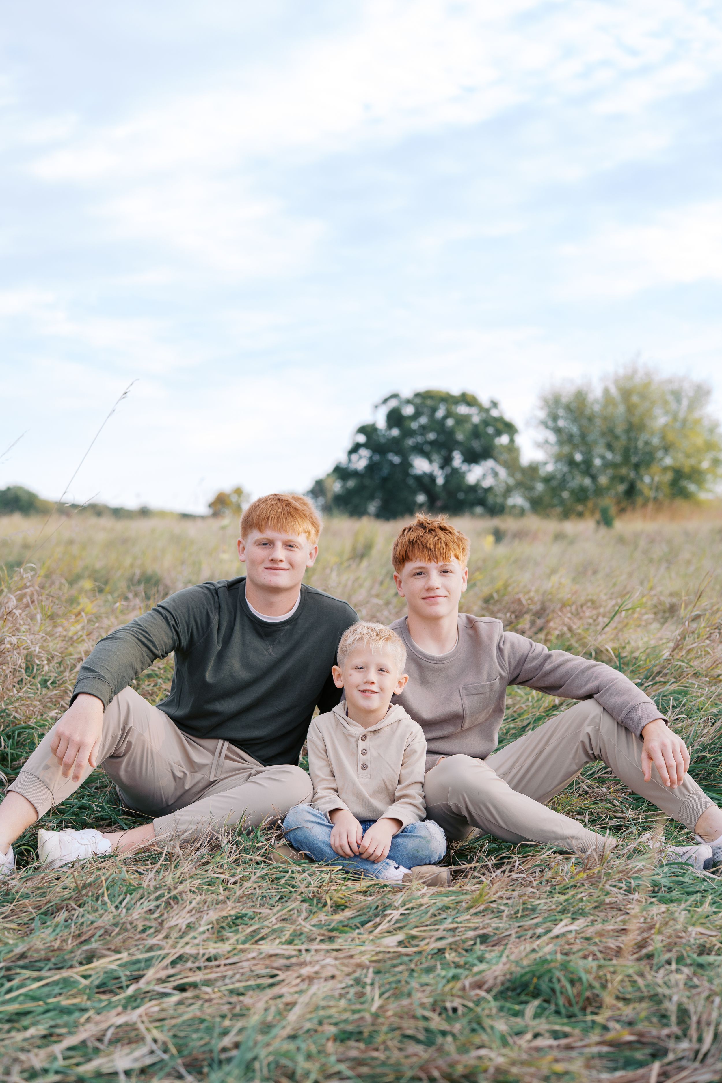 Casual family portrait with everyone lounging in the grass together.