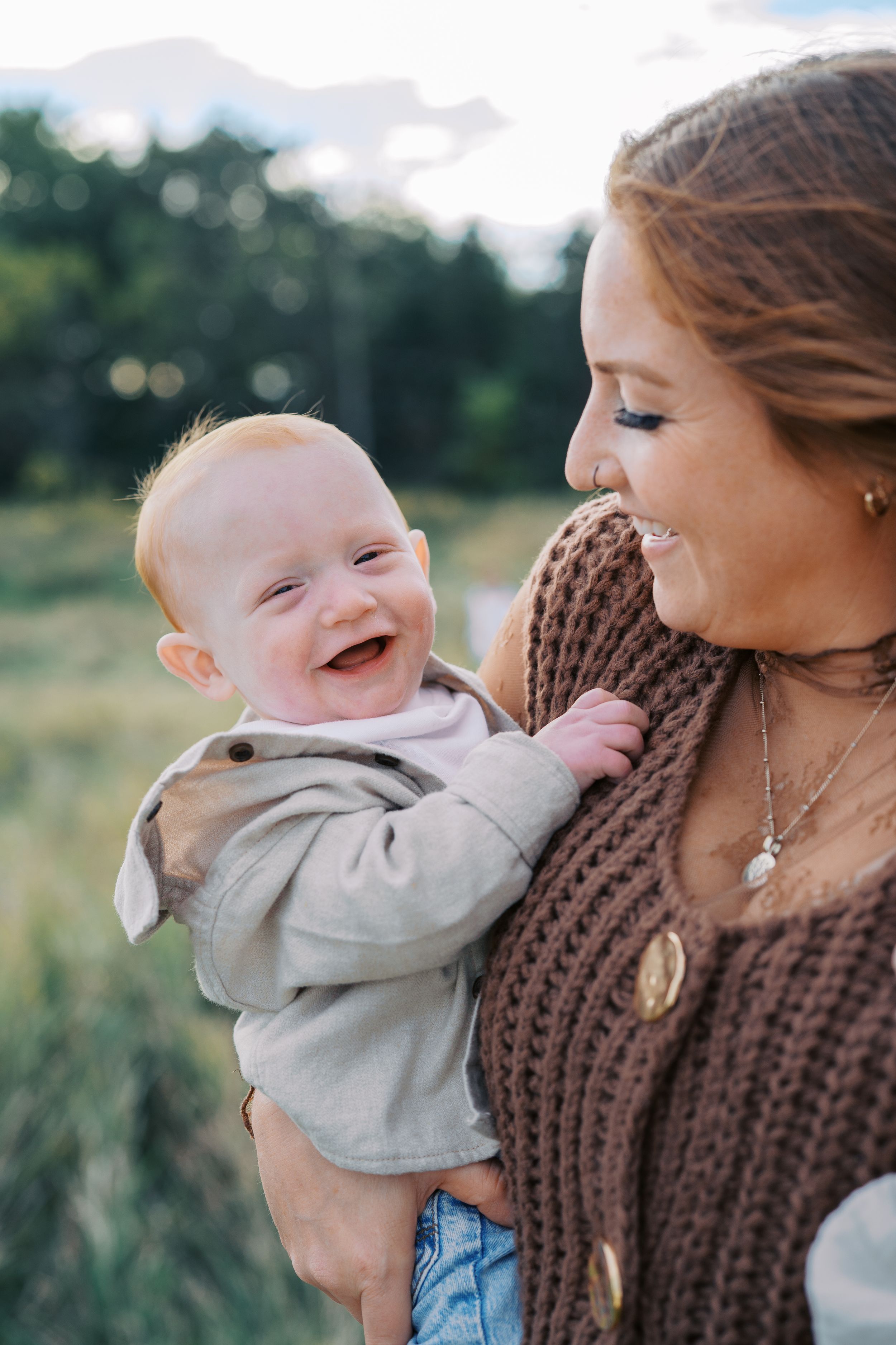 Sweet candid moments between parent and baby wearing a knit sweater outdoors.