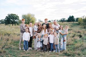 Group portrait of people in casual attire standing together on a natural hillside landscape.