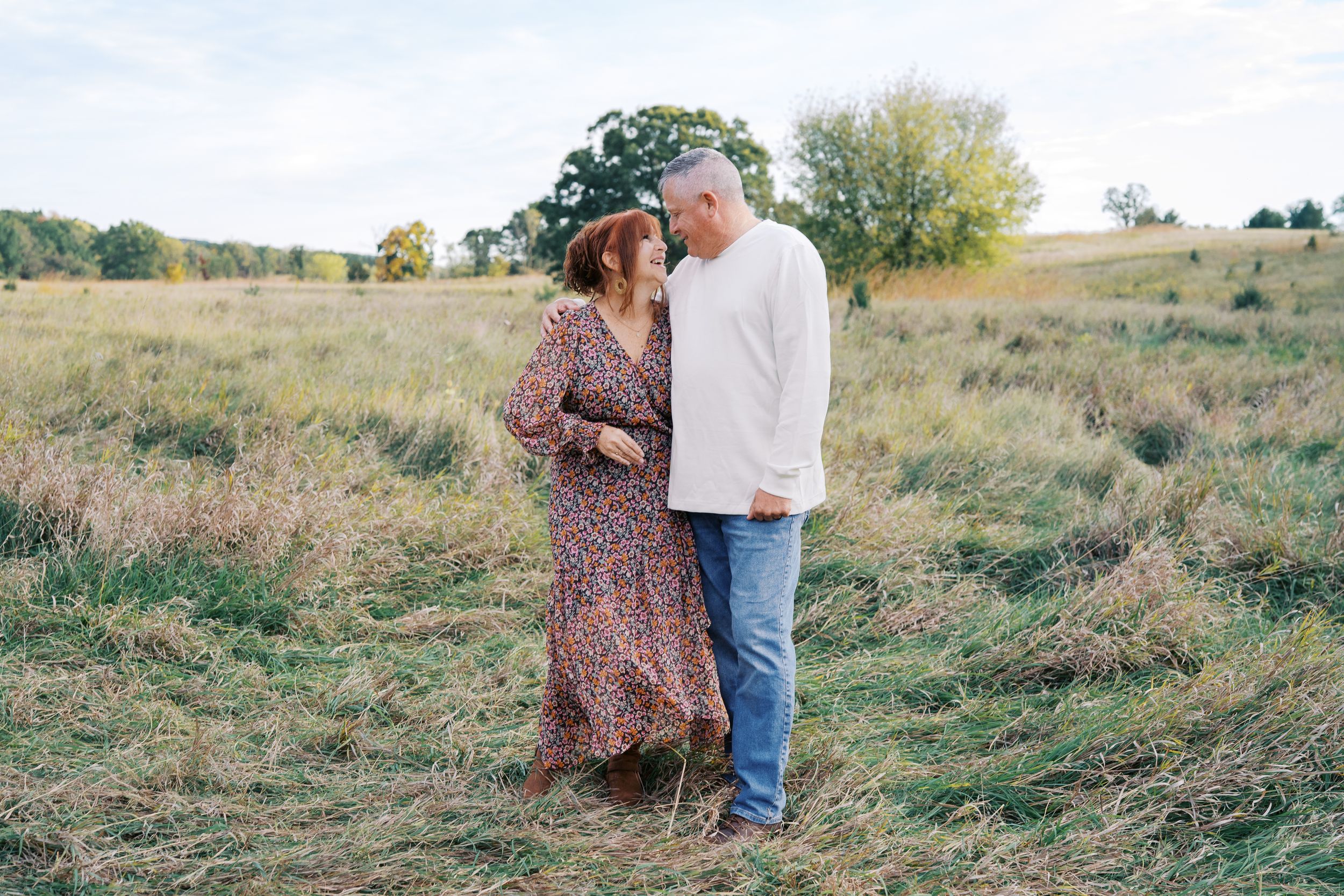 Candid outdoor family photo session showing people interacting naturally on a grassy slope.