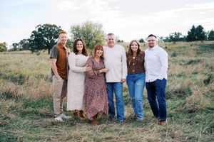 Extended family gathering outdoors in coordinated neutral tones.