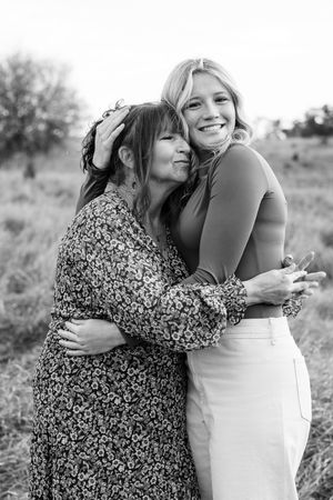 Two people share a warm embrace while laughing together in an outdoor setting.