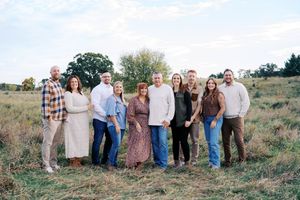 Extended family poses together for a group portrait in a rustic outdoor setting.