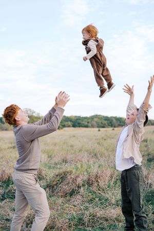 A series of four photos showing joyful moments in a meadow as a teddy bear is playfully tossed in the air.