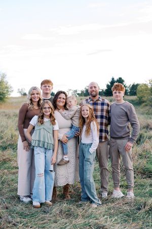 Large family group posed together on a hillside in casual attire.