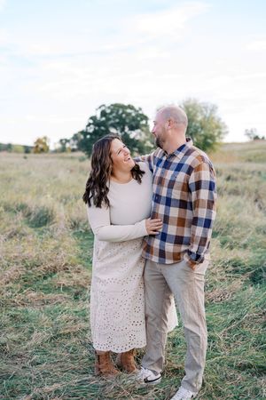 A couple shares a joyful moment while embracing in a field during an outdoor photoshoot.