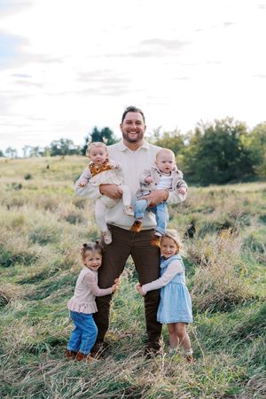 A playful family moment captured in a grassy field during golden hour.