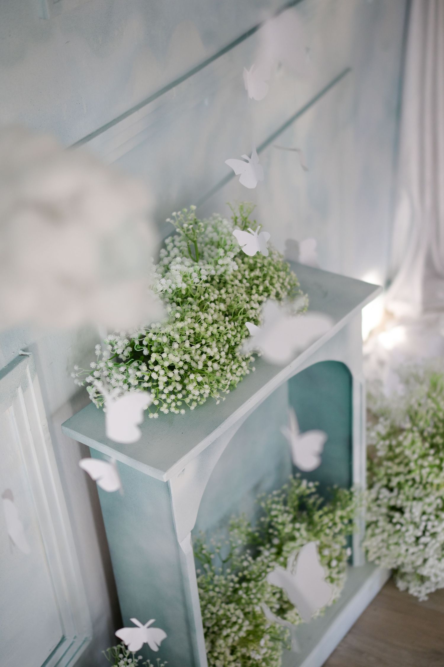 White butterflies and delicate baby's breath flowers create an ethereal display against a soft blue-tinted backdrop.