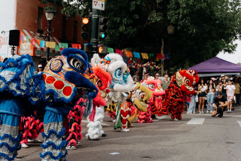 Colorful Chinese lion dance costumes and props lined up outdoors during a cultural festival performance.