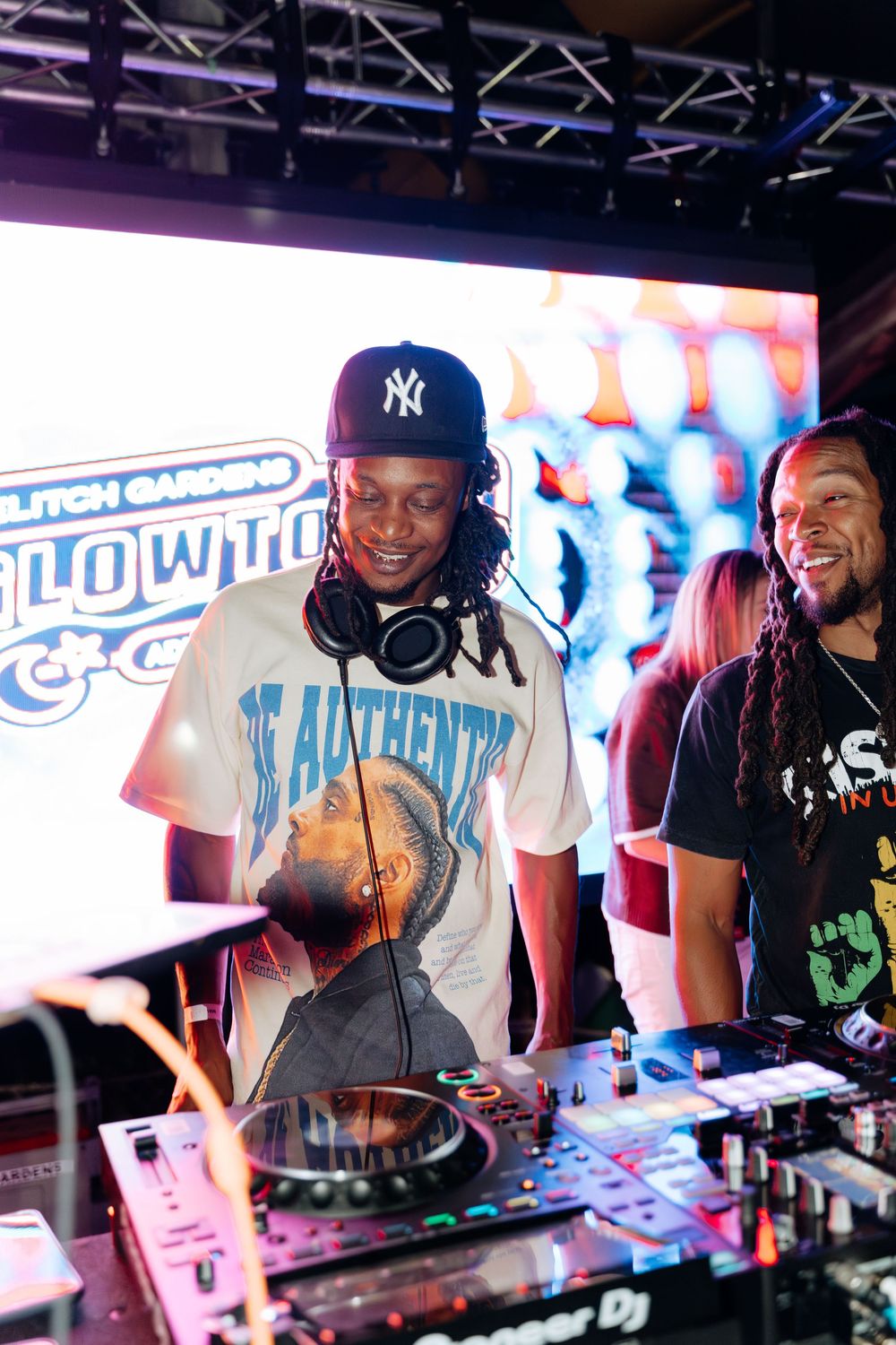 DJ performs at a nightclub using turntables and mixers under colorful lighting at an energetic party event.