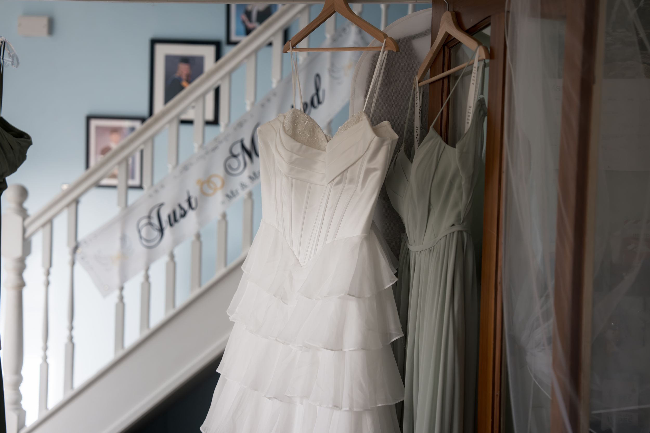 A row of elegant wedding dresses displayed on hangers in a bridal boutique with natural lighting streaming through windows.