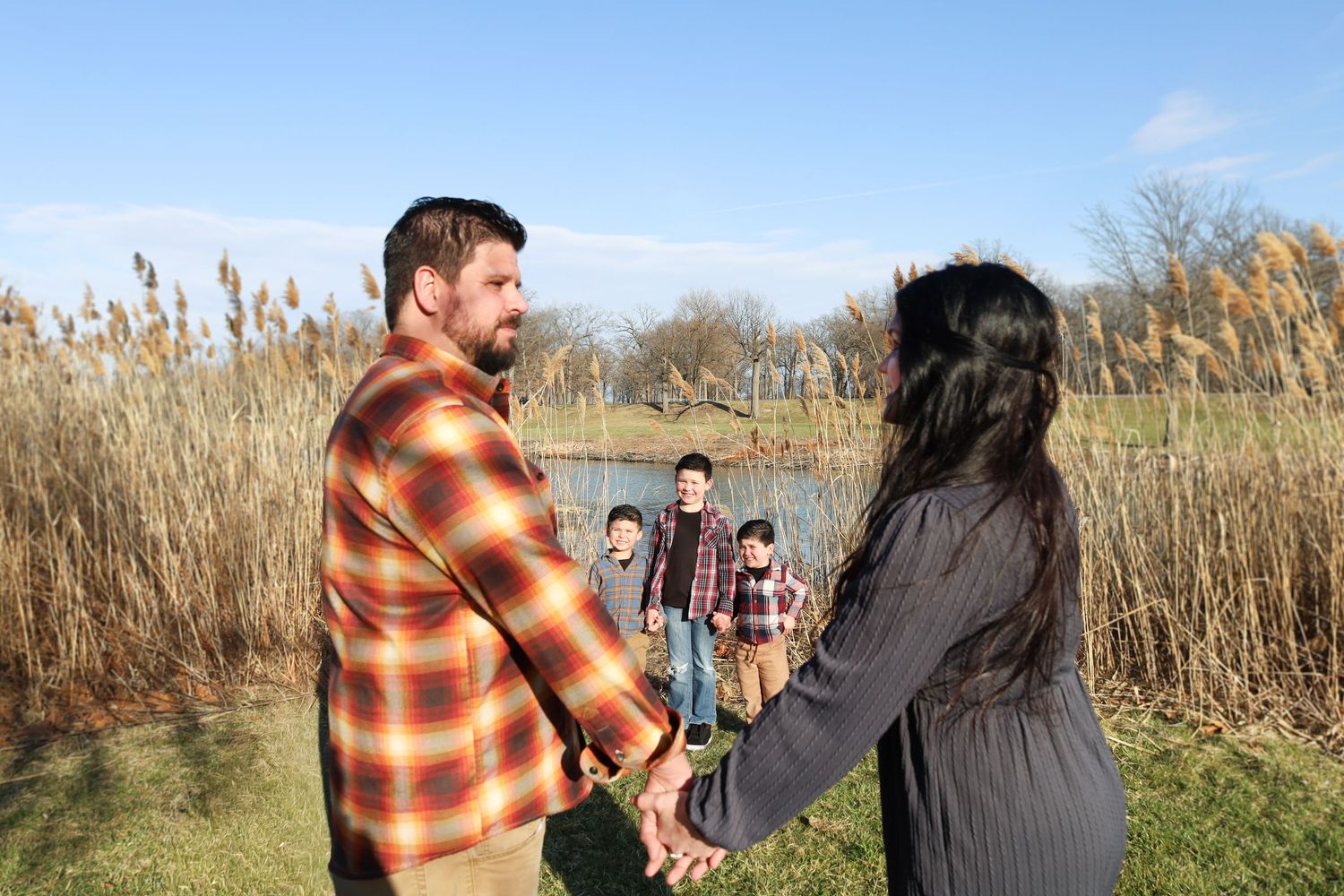 Candid moments captured in a field with cattails and autumn colors during golden hour.