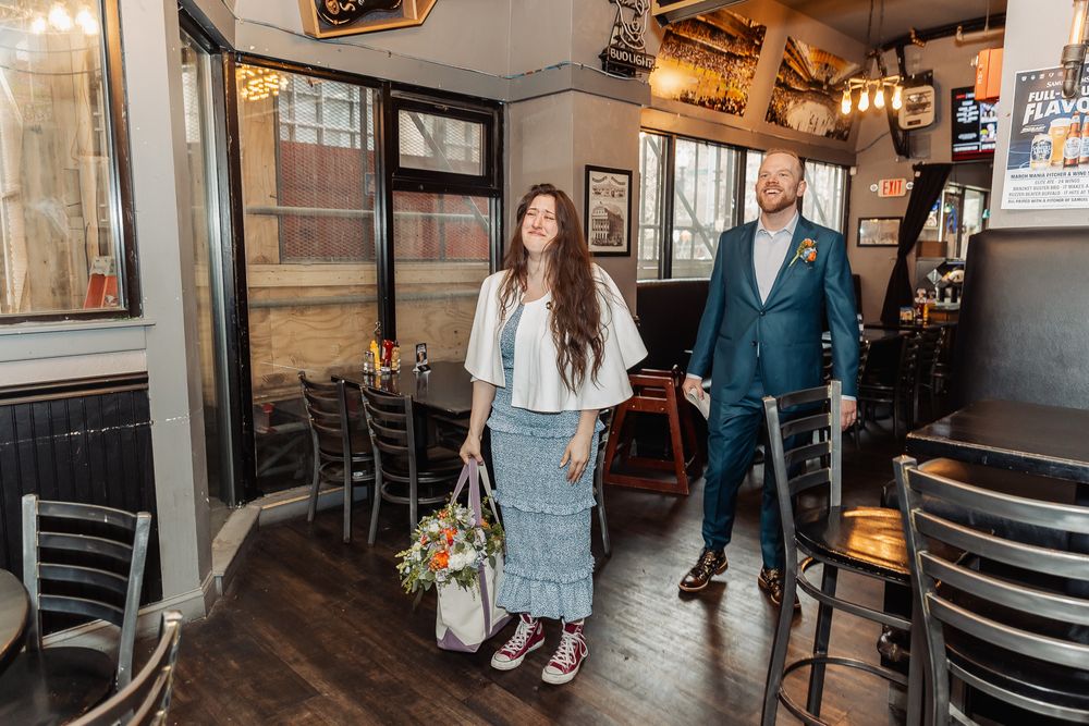 Couple walking hand-in-hand through a rustic restaurant interior, woman holding a colorful bouquet.