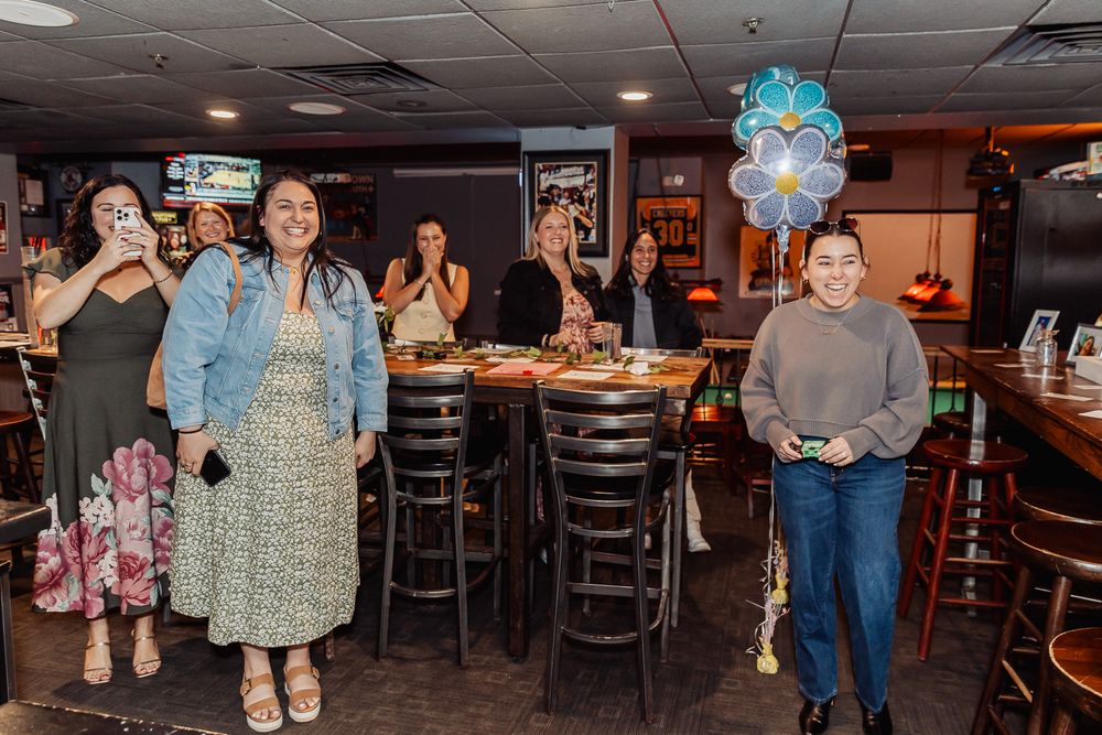 Women celebrating a birthday party in a restaurant bar with blue balloons and festive decorations.