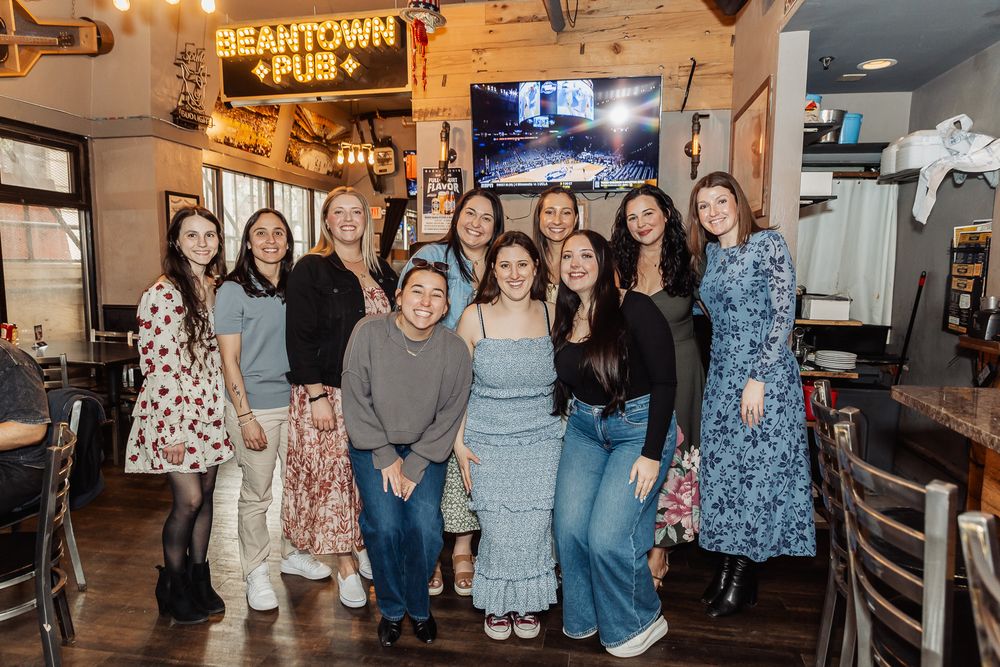 Group of women smiling together inside Beantown Pub restaurant, posing for a group photo.