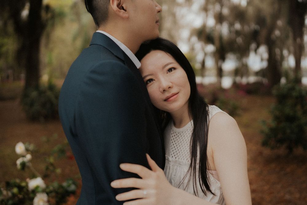 A couple in formal attire embraces intimately during an outdoor autumn photoshoot.