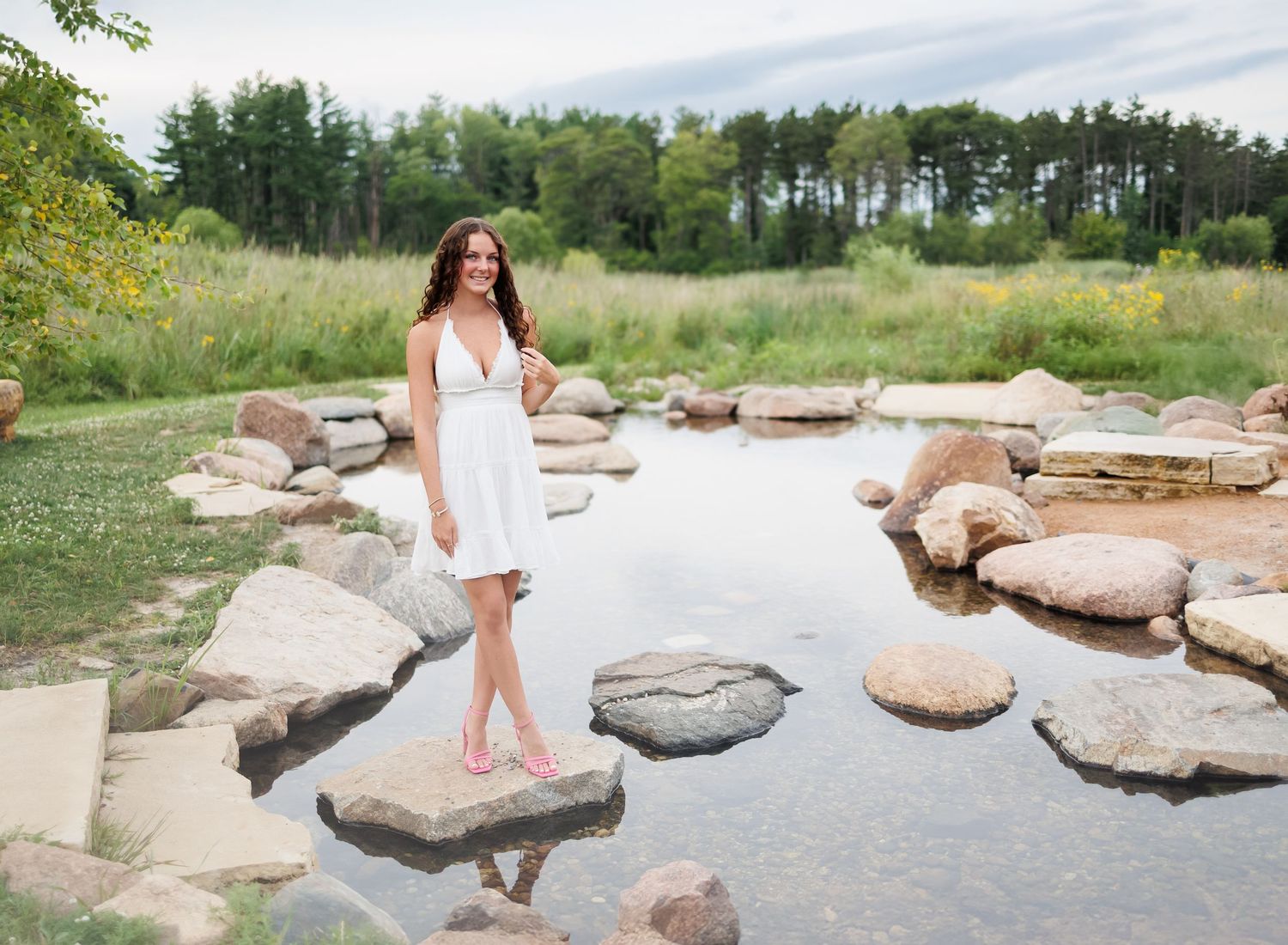 An image showing a senior girl walking across large stepping stones in a scenic natural setting.