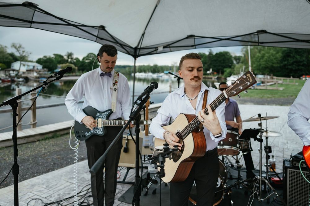 Live band performs under white canopy tents at an outdoor event.