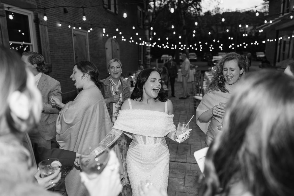 Joyful crowd dances together under twinkling lights at a nighttime celebration.