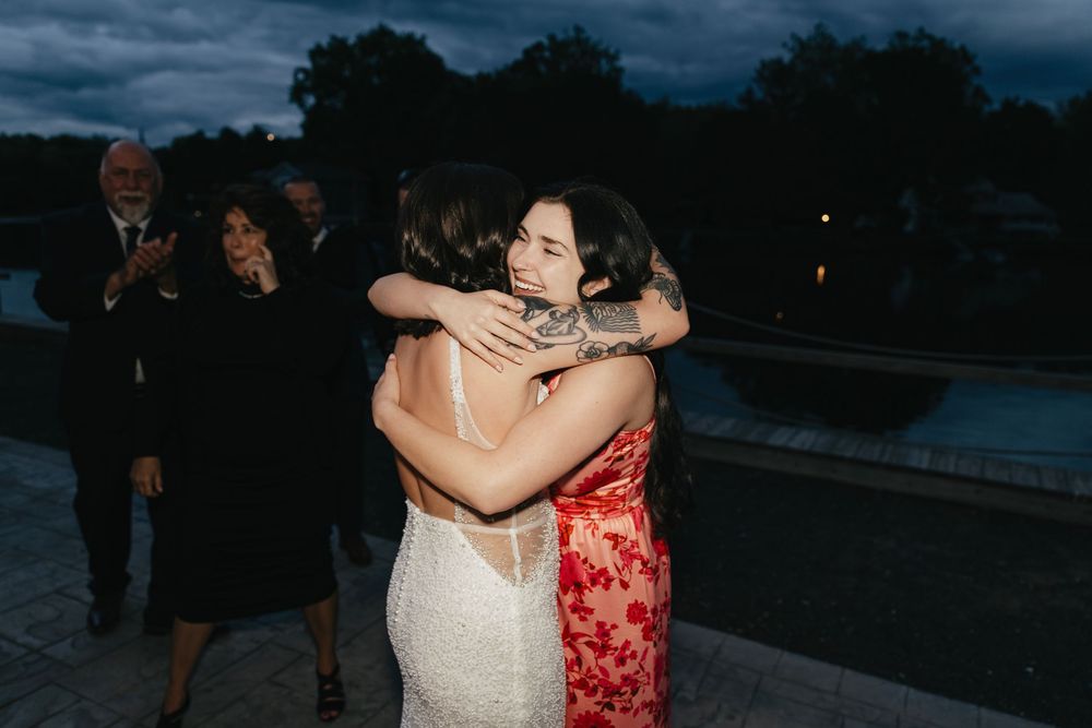 Wedding guests embracing during an emotional moment at dusk outdoors.
