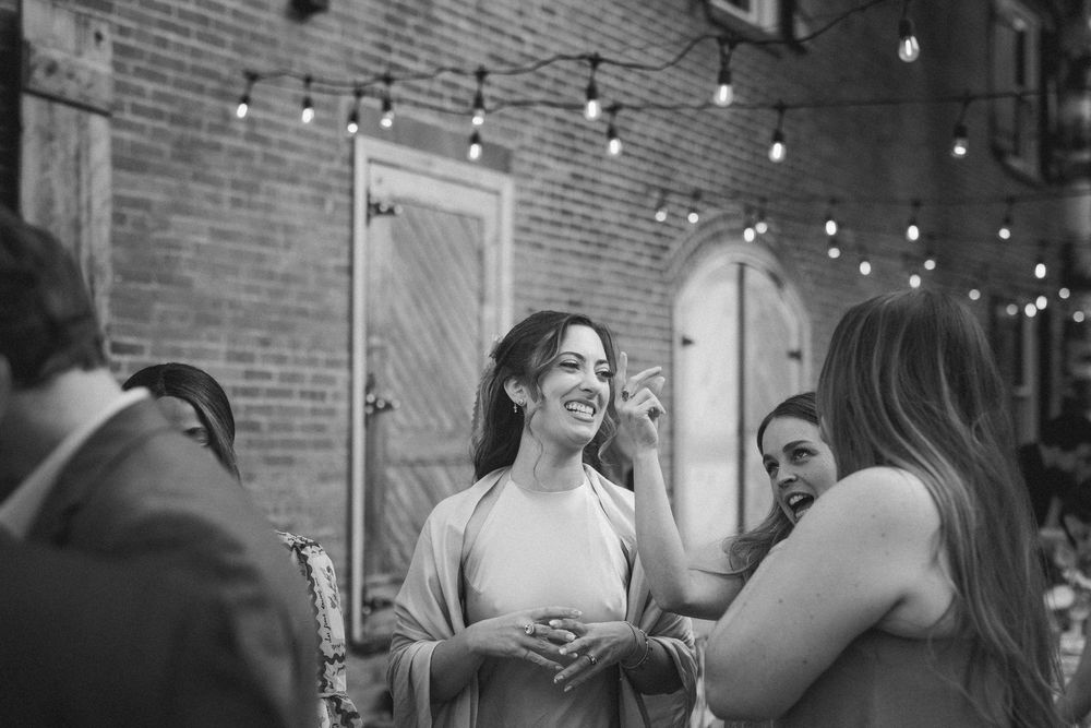 People dancing and celebrating at an indoor event with string lights and brick walls in the background.